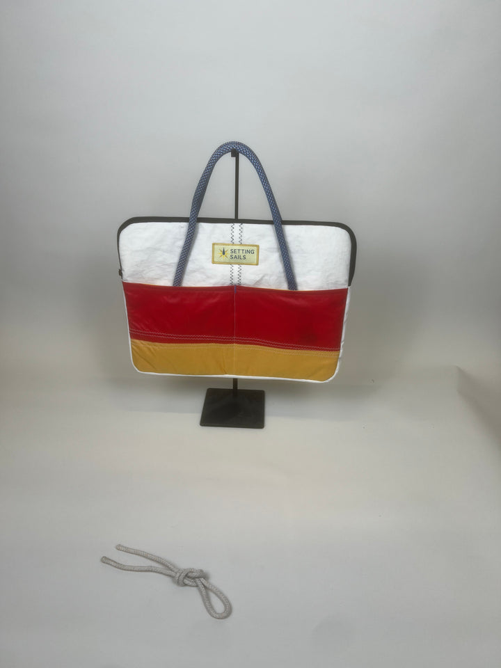 Laptoptas van gerecycled jachtzeil met rood en geel vlak en blauwe handvatten