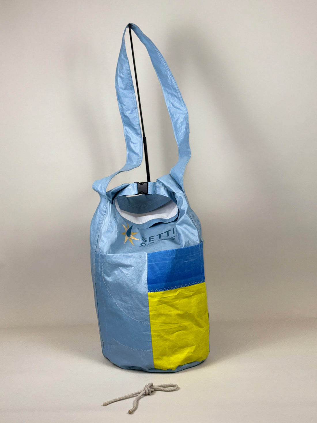 Plunjetas van lichtblauw gerecycled jachtzeil met blauw en geel vlak, achterkant en opening